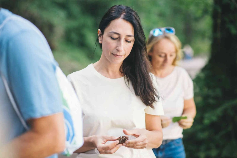 Frau steht in der Gruppe und schaut auf eine kastanie